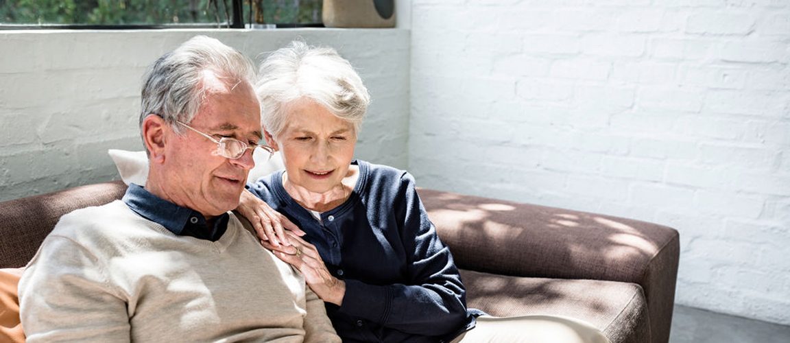 Retired couple sitting on sofa reading