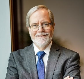 White man with glasses smiles at camera