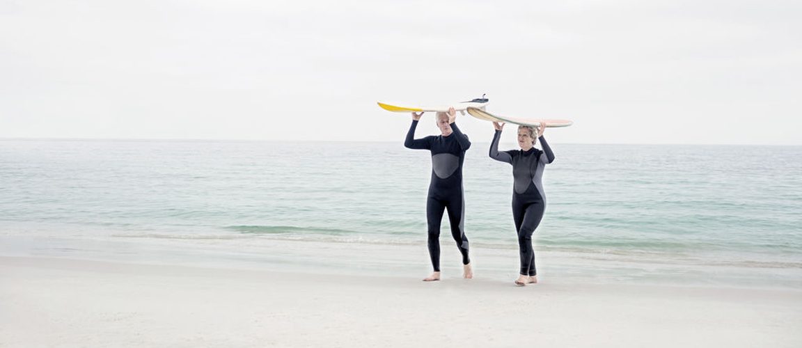 Retirement couple holding surfboards